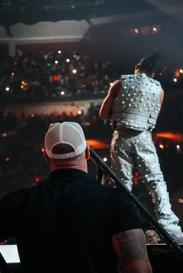 Close protection agent watching from the side of the stage during a sold-out arena concert